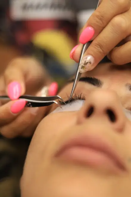Esteticista con pinzas trabajando las pestañas de una clienta