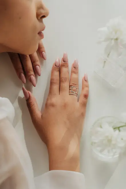 Manos con manicura natural entre flores blancas